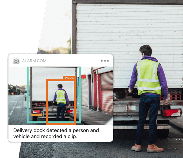 A person in a high-visibility vest stands near a truck, facing a delivery dock, while a digital interface highlights and identifies their presence.