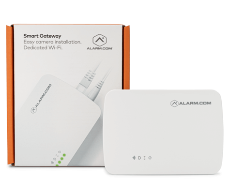 The image displays an "Alarm.com" Smart Gateway device next to its packaging, which emphasizes easy camera installation and dedicated Wi-Fi functionality.