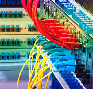 The image shows a network switch with multiple Ethernet cables connected. Red, yellow, and blue cables are organized in rows, indicating data communication infrastructure.